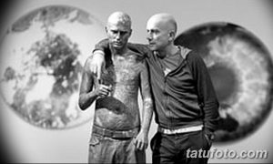 Фото тату: два мужчины с обширными татуировками на теле, включая изображения черепов и биомеханических элементов. Фон размыт, с изображением глаза.